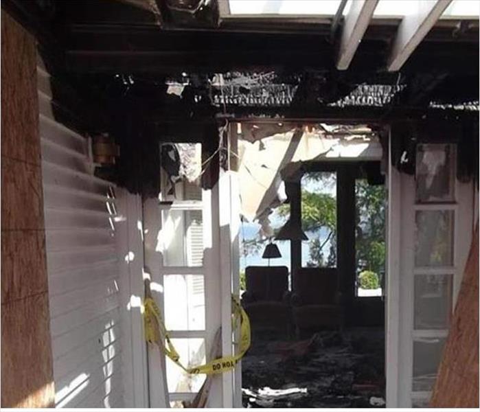 black, burnt debris on ceiling and walls, boarded window