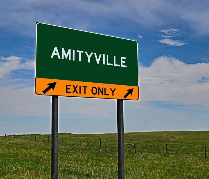 A green road sign that says Amityville 